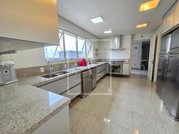 Cozinha ampla com bancadas de pedra, armários e janelas.