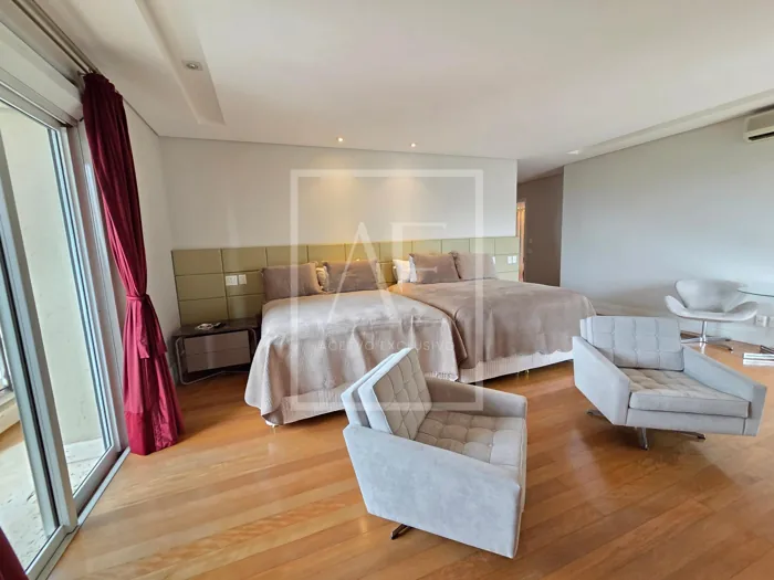 Suíte ampla com cama, poltronas e varanda.